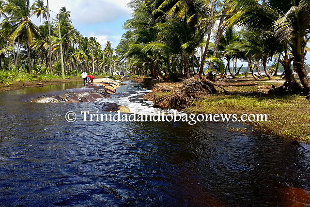 Swamp water flows over the Manzanilla Road into the collapsed section of the road towards the sea