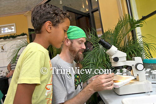 A young curious onlooker observes how Mike Rutherford examines a specimen
